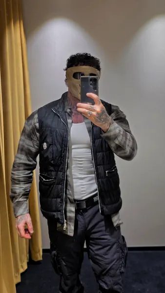 Zade, tan balaclava. Mirror selfie in tactical gilet and check shirt.