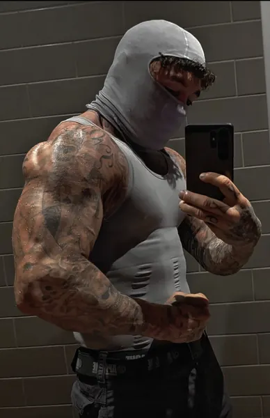 Zade, grey balaclava. Mirror selfie in grey vest against tiled wall.