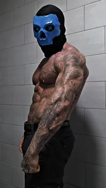 Zade, blue skull mask. Shirtless side profile against white tiles.