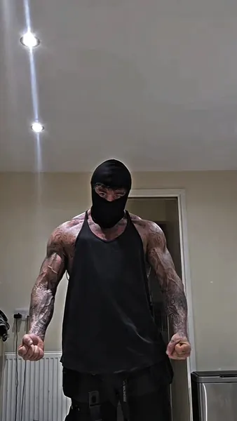 Zade, black balaclava. Black vest, flexing at home.