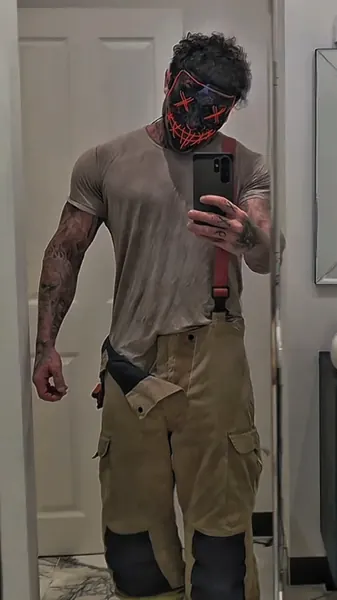 Zade, red LED purge mask. Mirror selfie in tee, braces and cargo trousers.