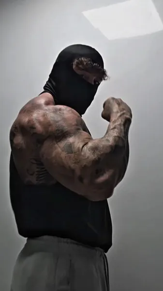 Zade, black balaclava. Side bicep flex, black top.