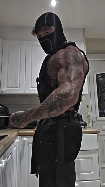 Zade, black balaclava. Side profile in tactical vest, kitchen.