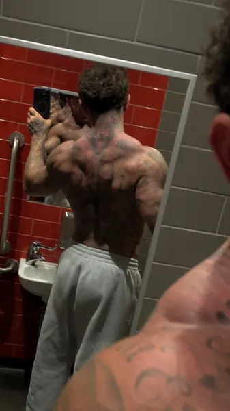 Zade, face hidden. Back view in mirror, red tiles.