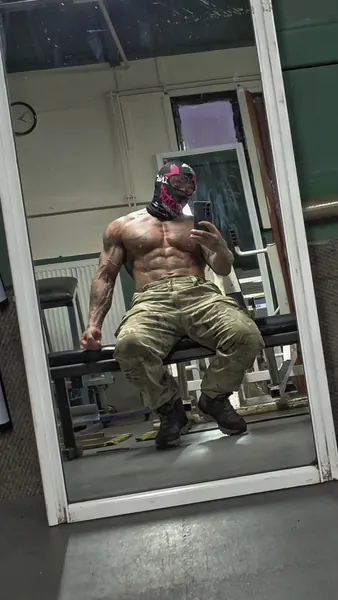 Zade, pink graphic face mask. Seated on gym bench, reflected in mirror.