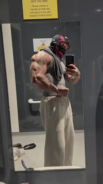 Zade, pink graphic face mask. Gym mirror selfie, vest and joggers.